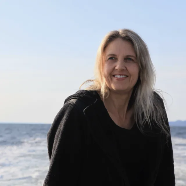 travel advisor Susan Anderson in a black sweatshirt on a beach