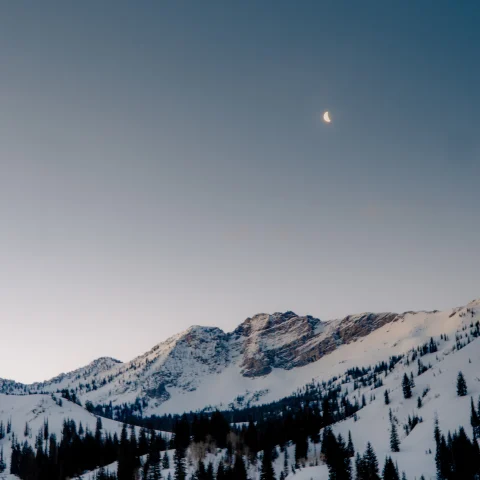 snow-covered mountain with the moon in the sky during sunrise