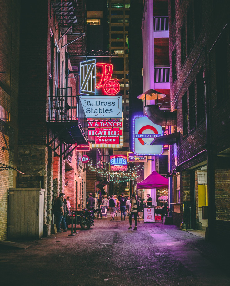 Bright signs with people walking on sidewalk at night