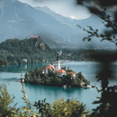 Island with red-brick houses and a church in the middle of Lake Bled in Slovenia. 