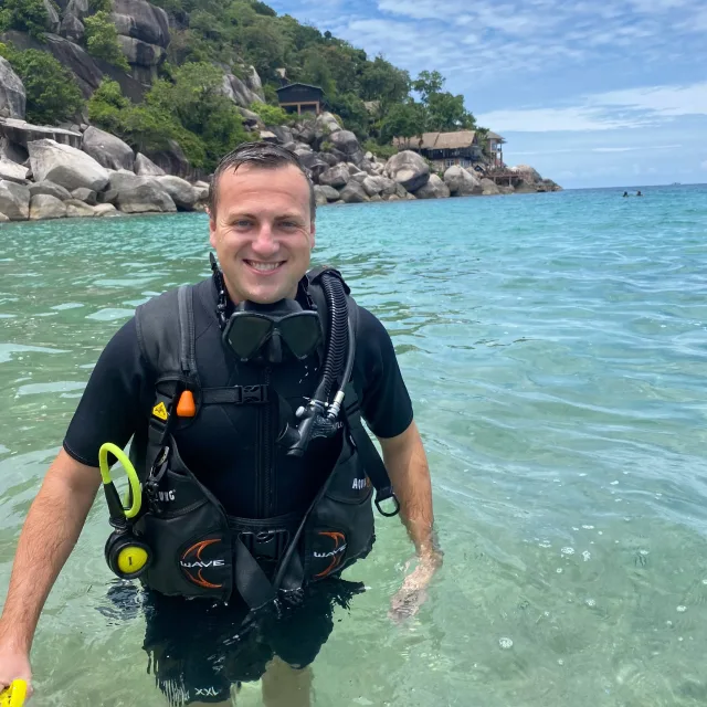 Travel Advisor Shane Sullivan in scuba diving attire standing in blue sea water. 