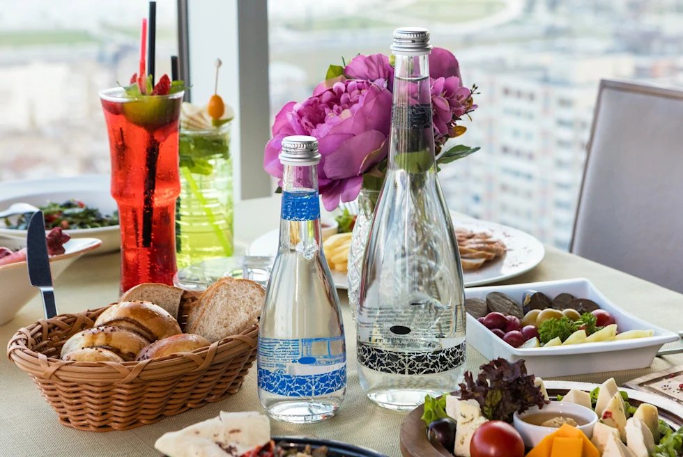 A table with bread, water and an assortment of cheeses. 