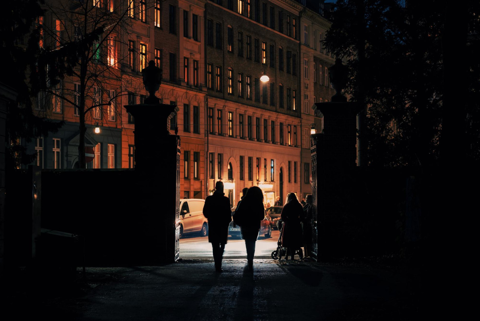 Couple walking into Assistens Cemetery at night.