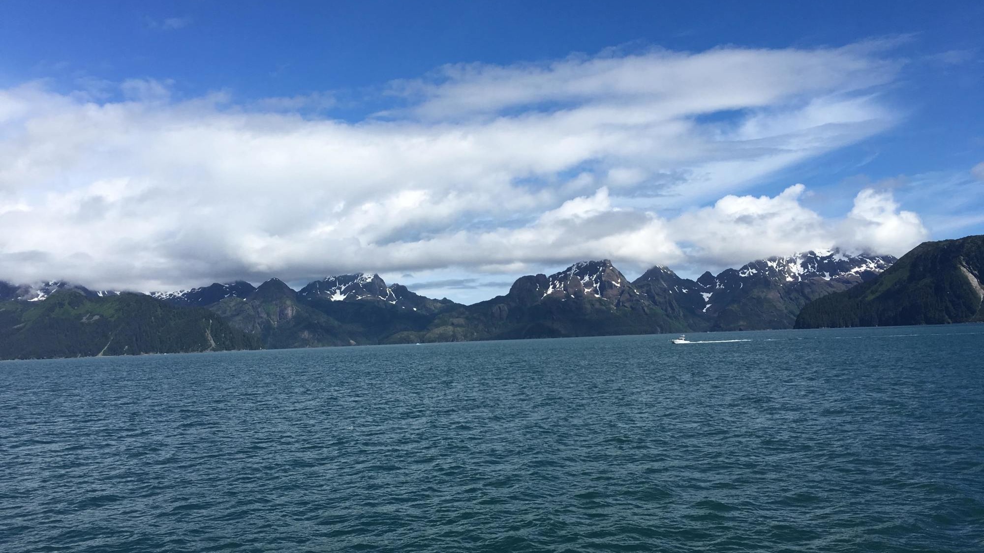 A water body with snow covered mountains at the back. 