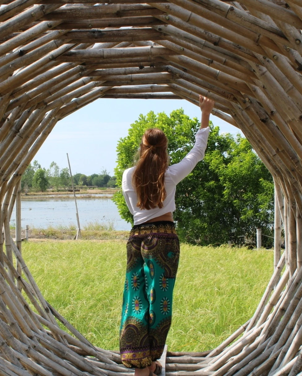 A person stands inside a circular wooden structure, gazing at a serene natural landscape.