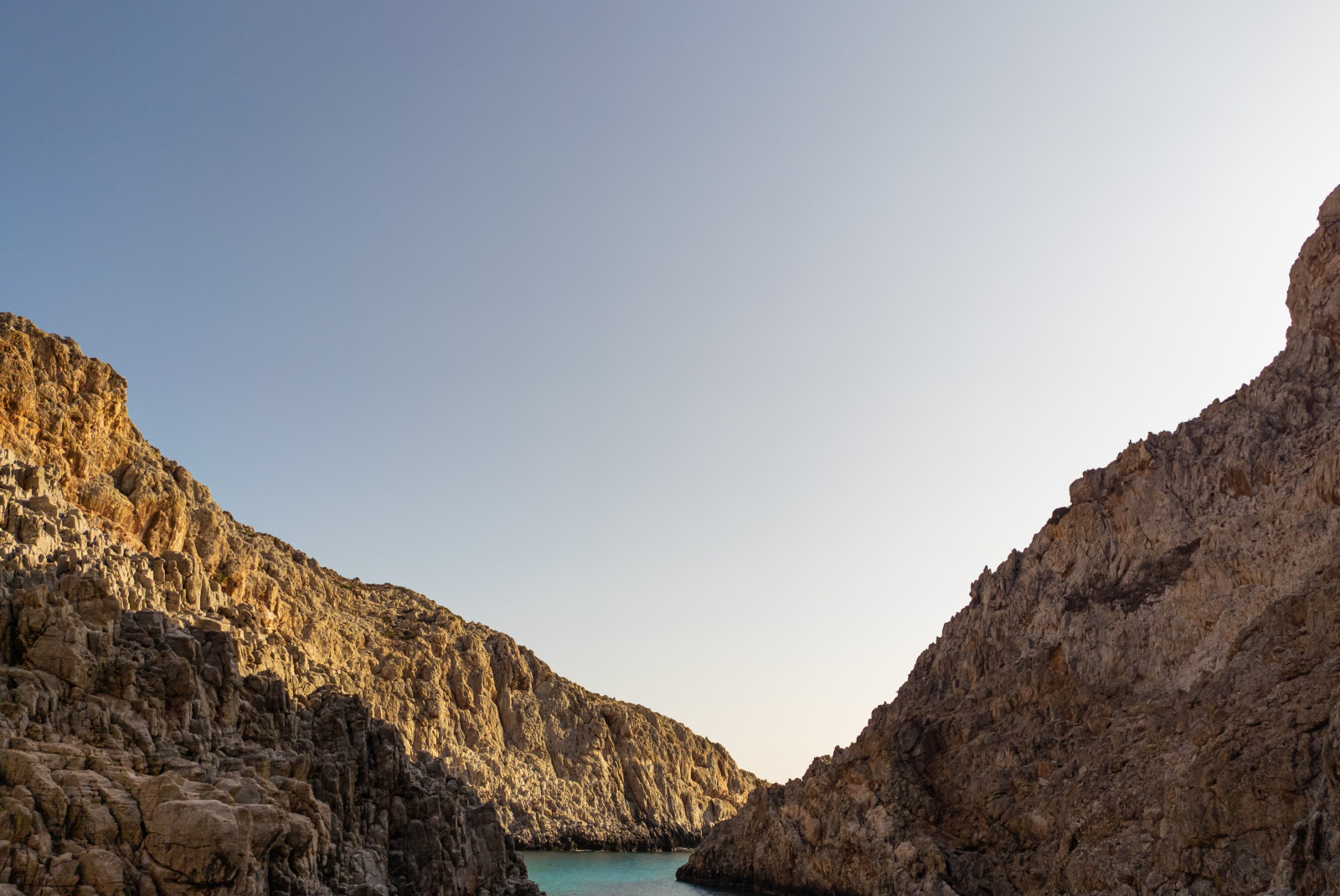 Three brown seaside cliffs in Crete with blue water