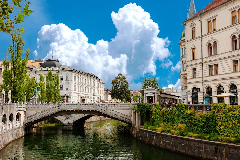 Body of water with a bridge next to buildings with blue skies during daytime