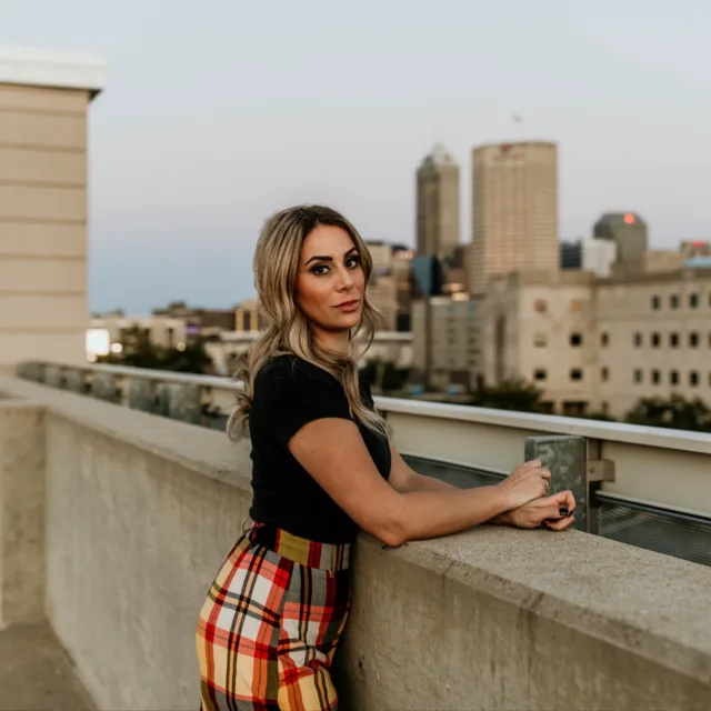 travel advisor Taylor Nefouse in a plaid skirt and black shirt on a rooftop