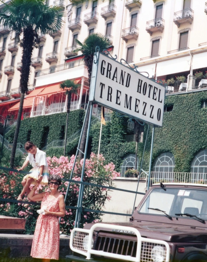two woman near a car in front of a grand hotel