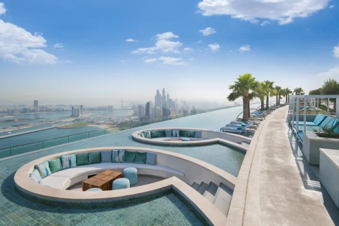 circular seating areas nestled in a pool overlooking the city and ocean below