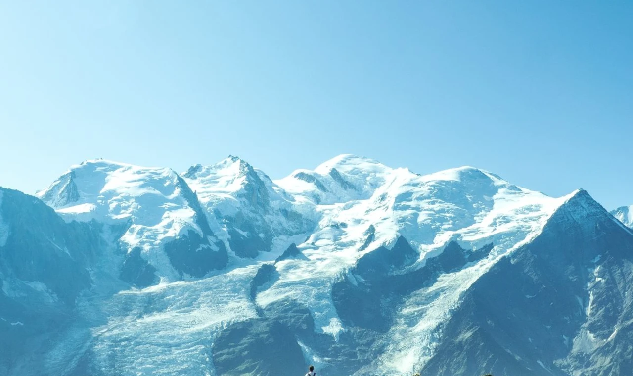Man standing on mountain overlooking snowcapped mountains in Chamonix.