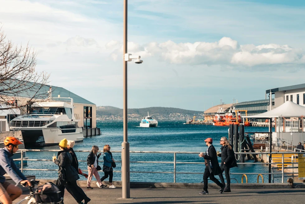A group of people walking down a street next to a body of water