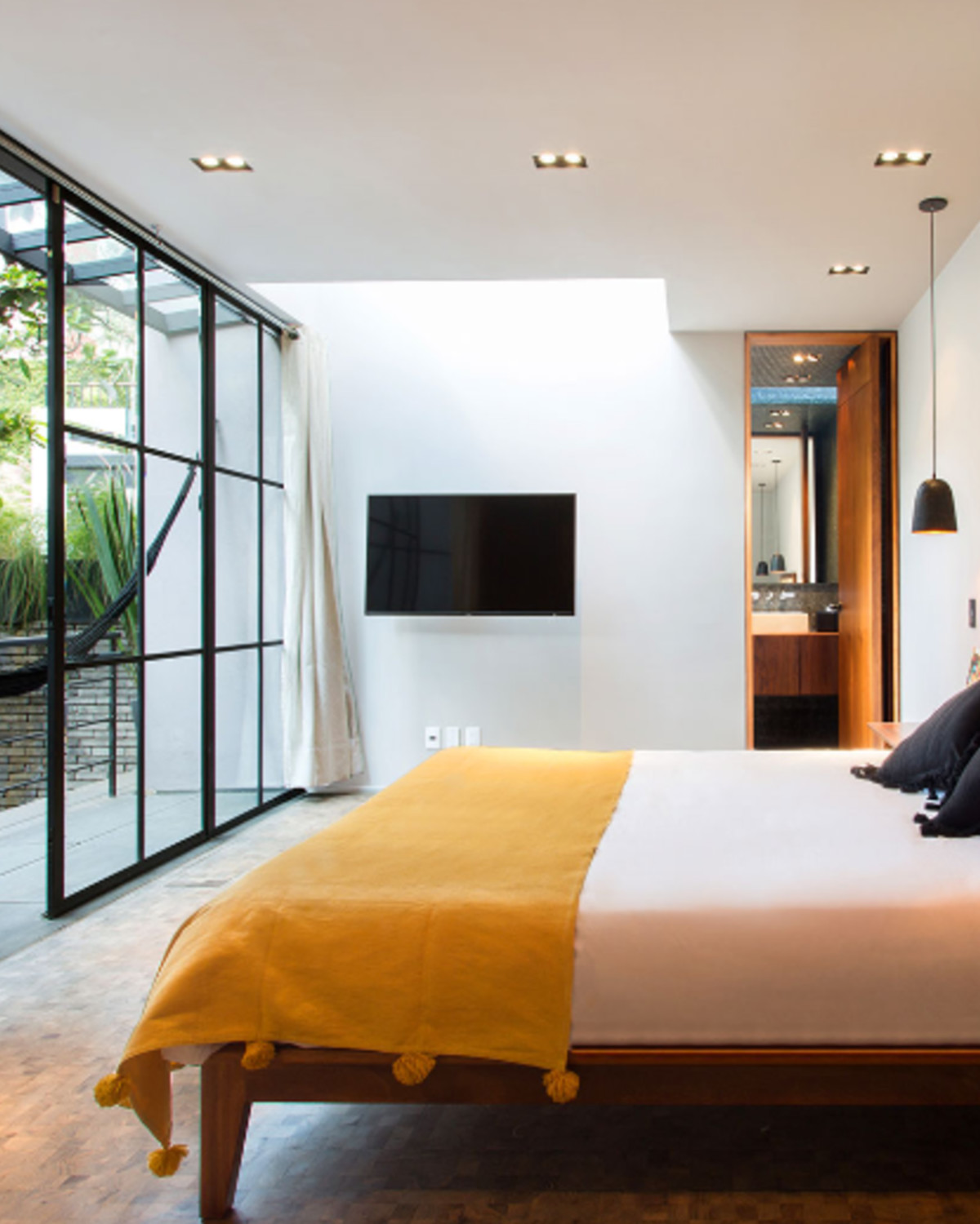 a bed with a yellow blanket overlooks a sleek patio
