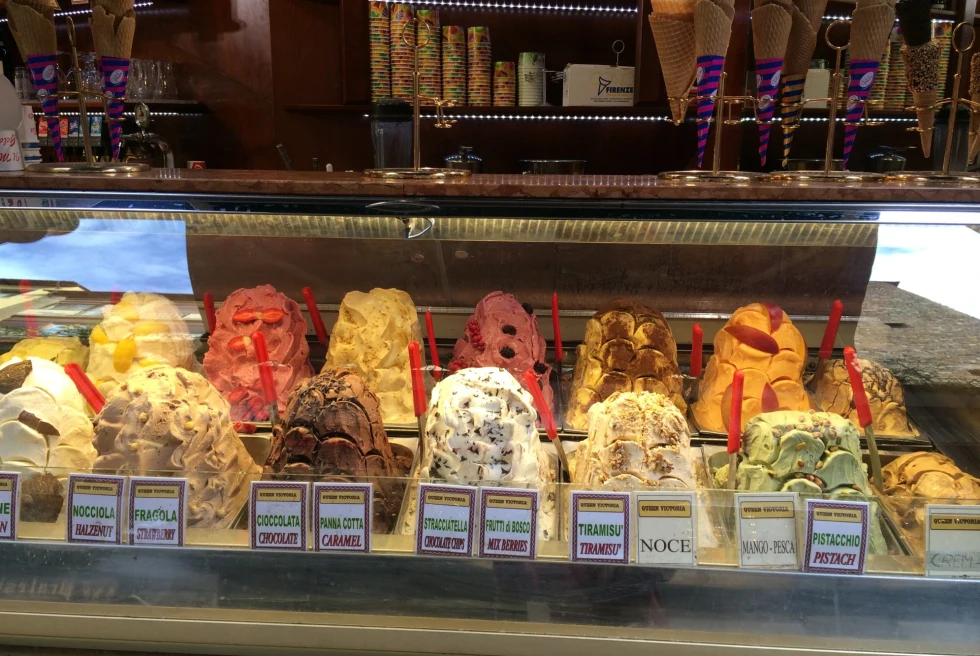 An array of gelato flavors behind a glass counter