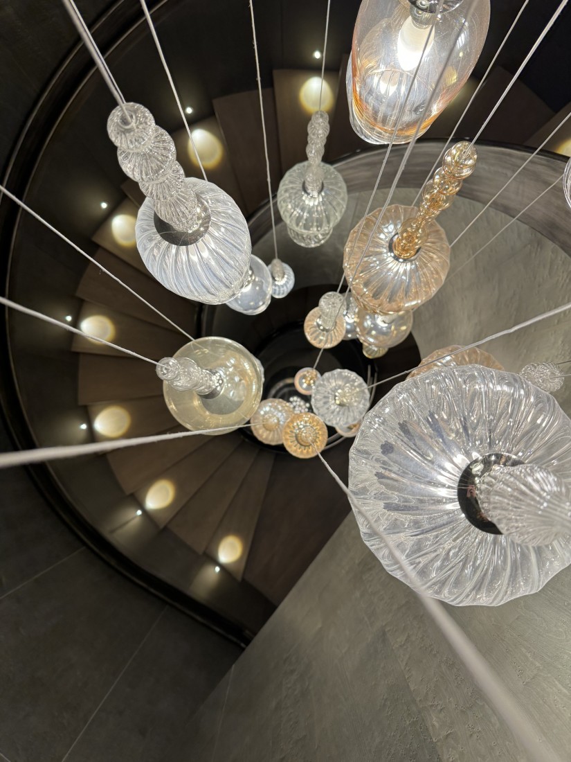 An above view of a chandelier hanging over a spiral staircase. 