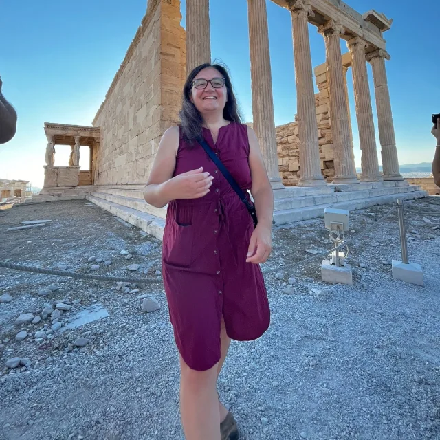 Travel Advisor Christina Loranz in a pink dress in front of Athens ruins.