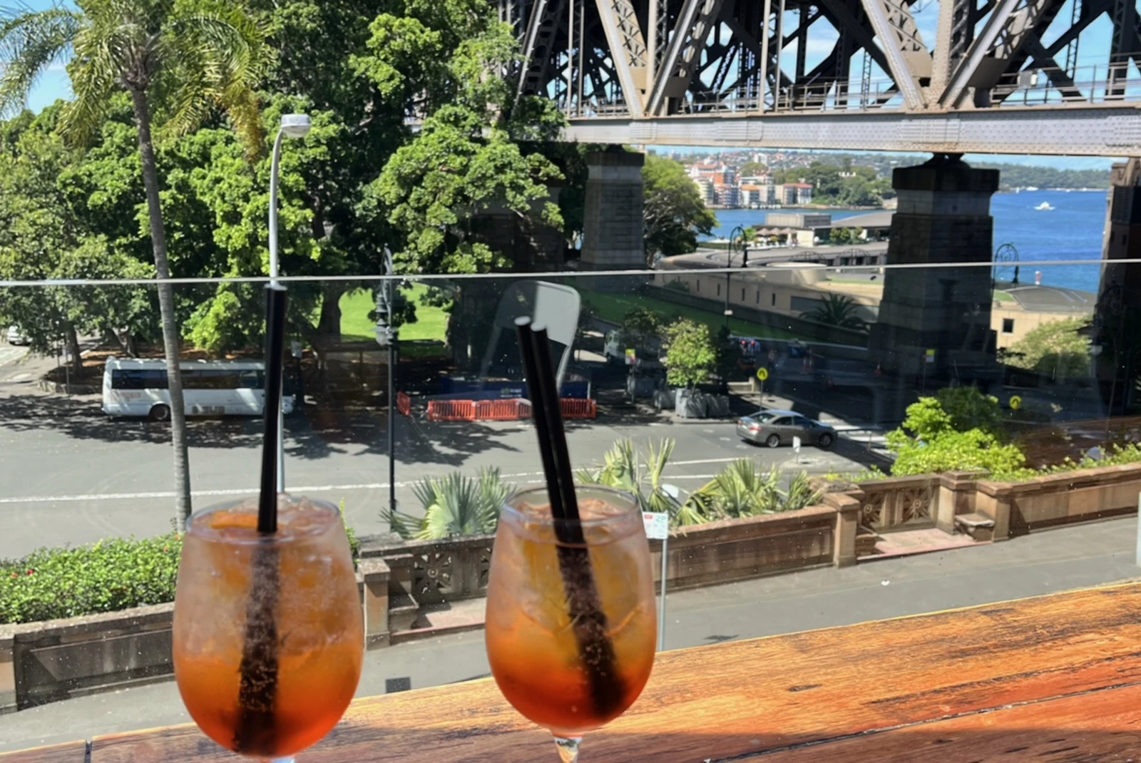 two drinks on a wooden table overlooking bridge and tree