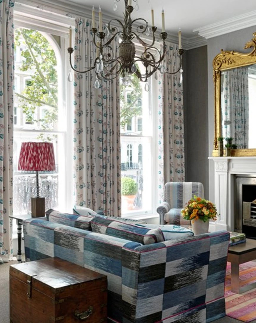 a luxe living room with an ornate chandelier and floor-to-ceiling windows