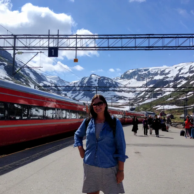 Jamie Kanehl standing by a red train with snow covered mountains in the background