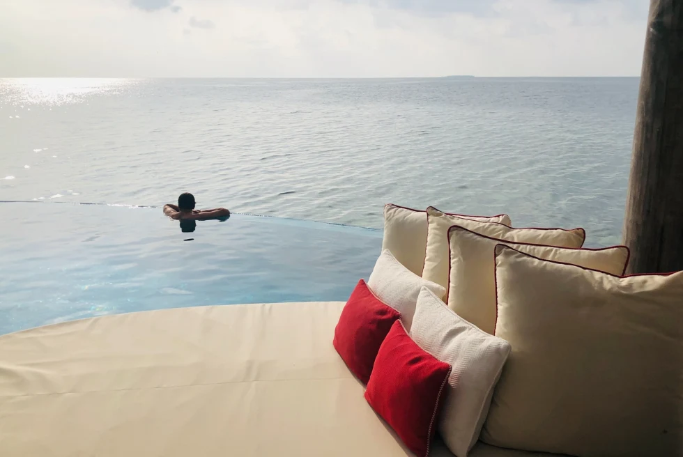 man in an infinity pool overlooking the ocean