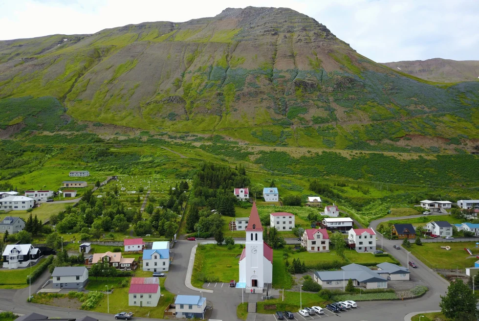 Neighborhood of houses at the base of a green, rocky hillside