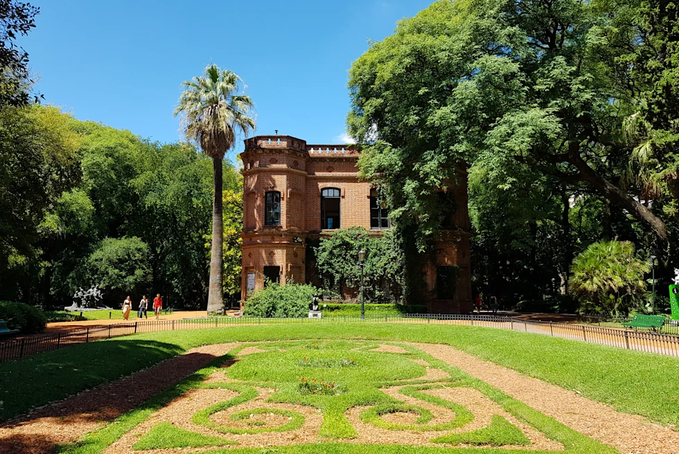 Park with green grass, trees and brick building on sunny day