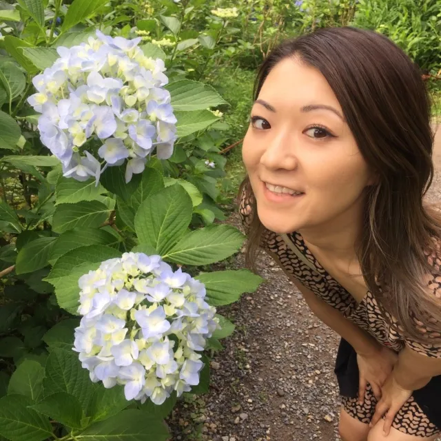 Aron Hibi posing in front of two hydrangea flowers. 