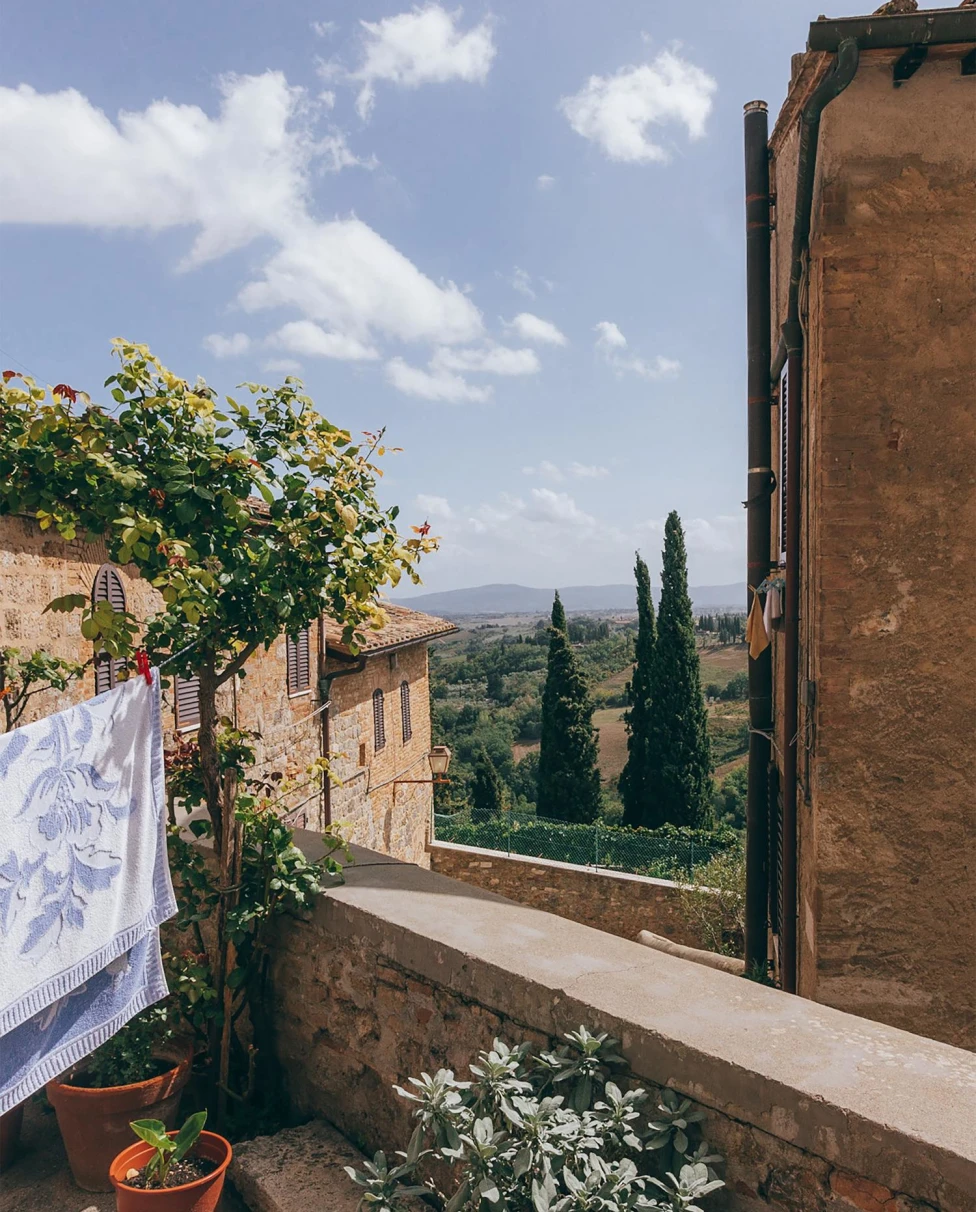 Rustic balcony of Siena in Italy's lush Tuscan hills on a sunny day.