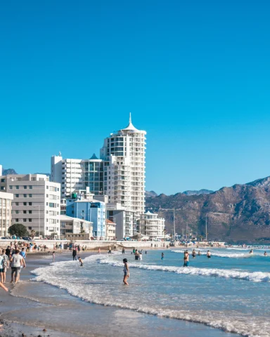 cape town south africa beach and city view of white buildings with people in the waves brown cliffs and blue water
