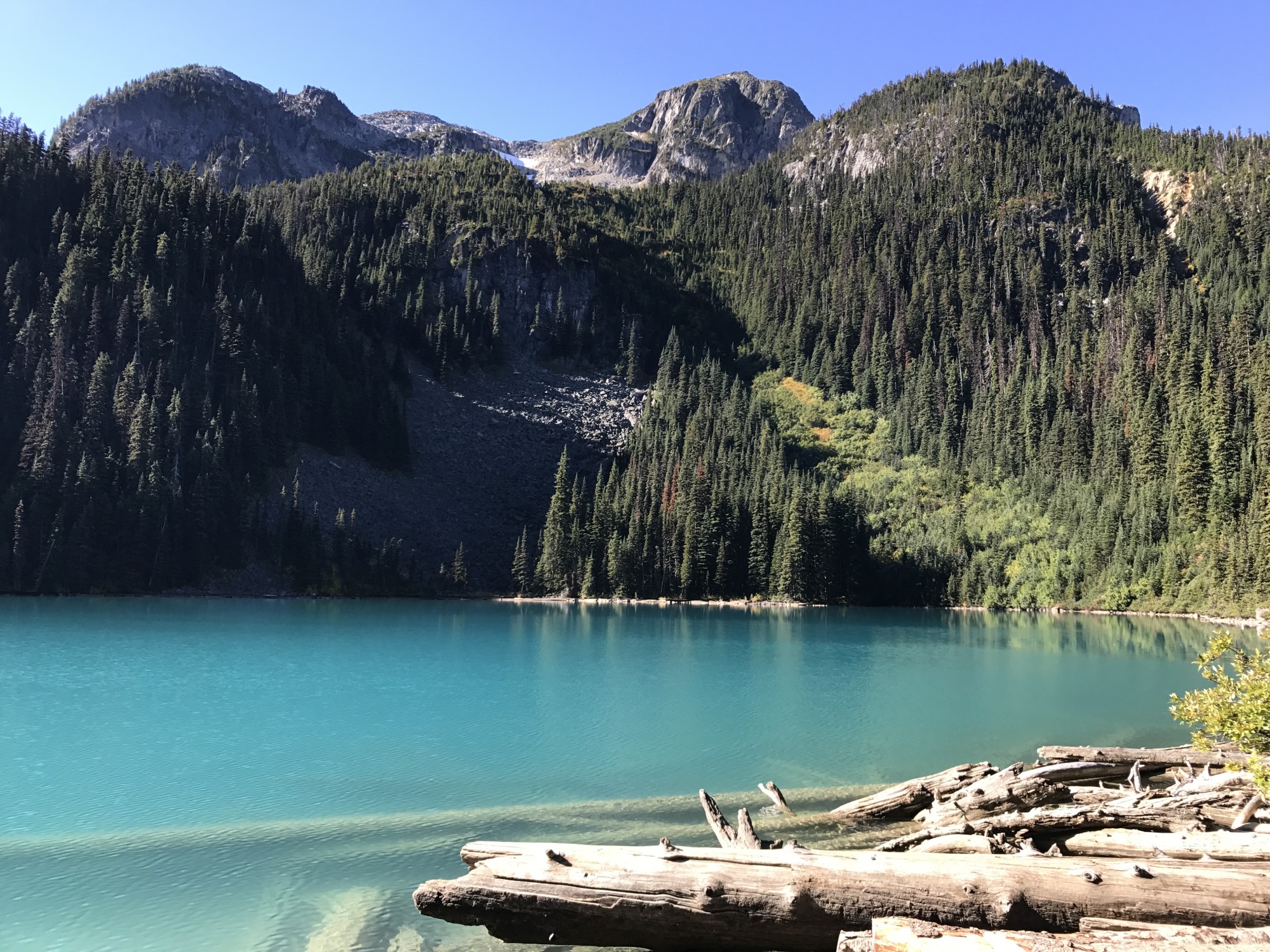light blue lake at the base of a mountain and forest