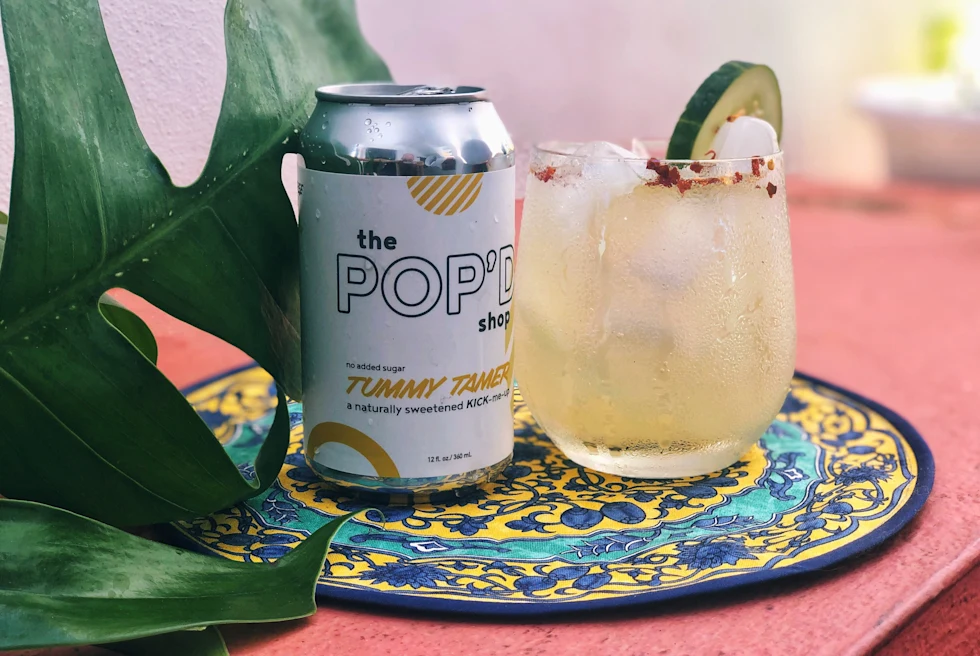 Two drinks on colorful plate on pink table next to green plant