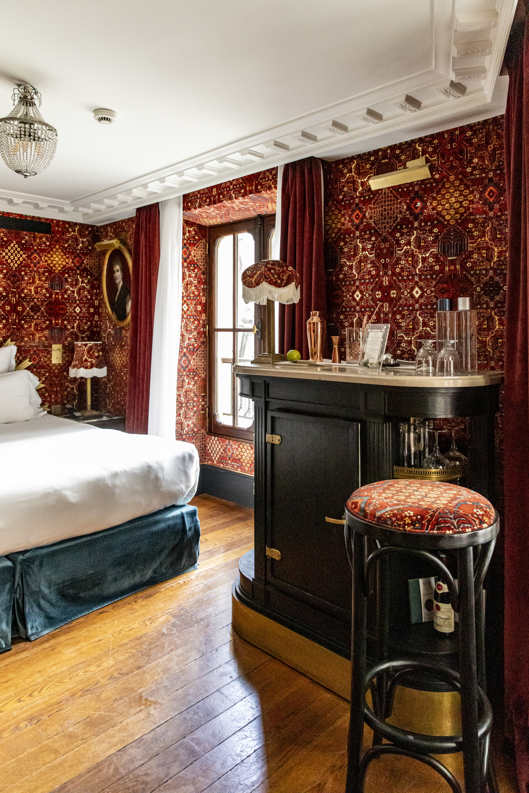 a luxe bedroom with vibrant red wallpaper and a private bar