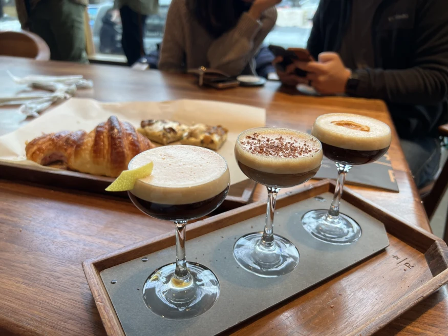 a flight of three frothy espresso cocktails in martini glasses