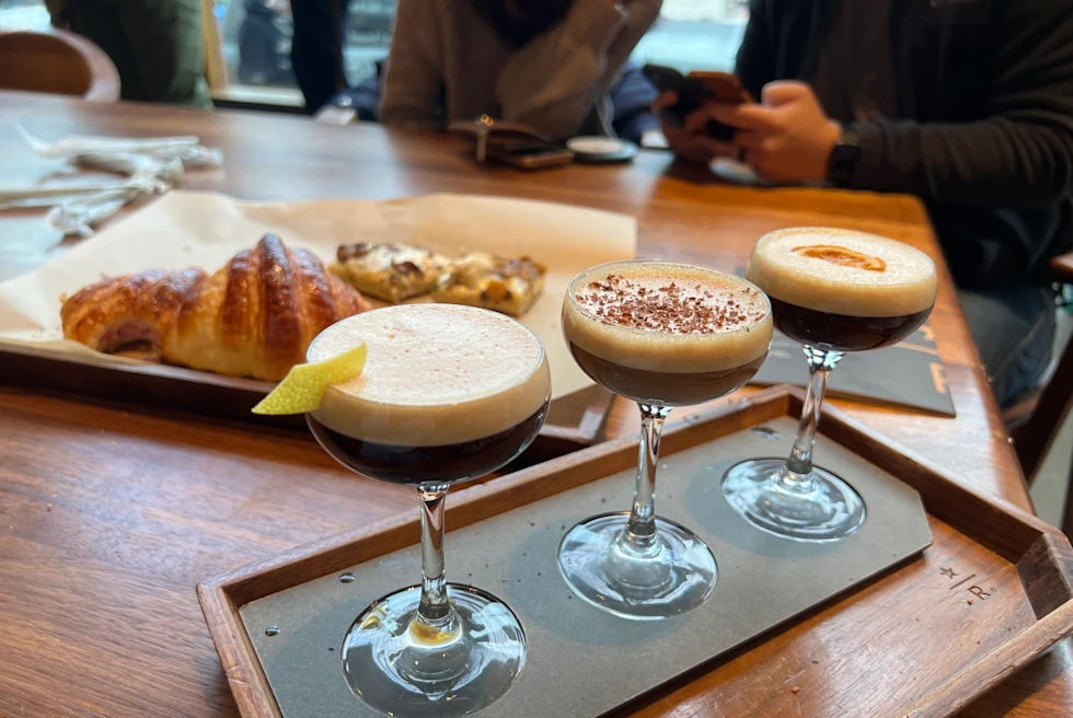 a flight of three frothy espresso cocktails in martini glasses
