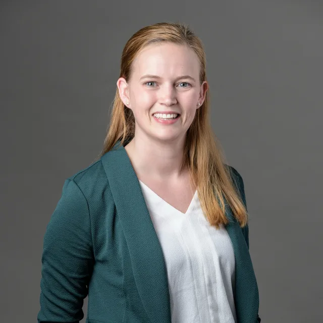 Travel Advisor Morgan Van Dame in a green blazer and white shirt in front of a grey background.