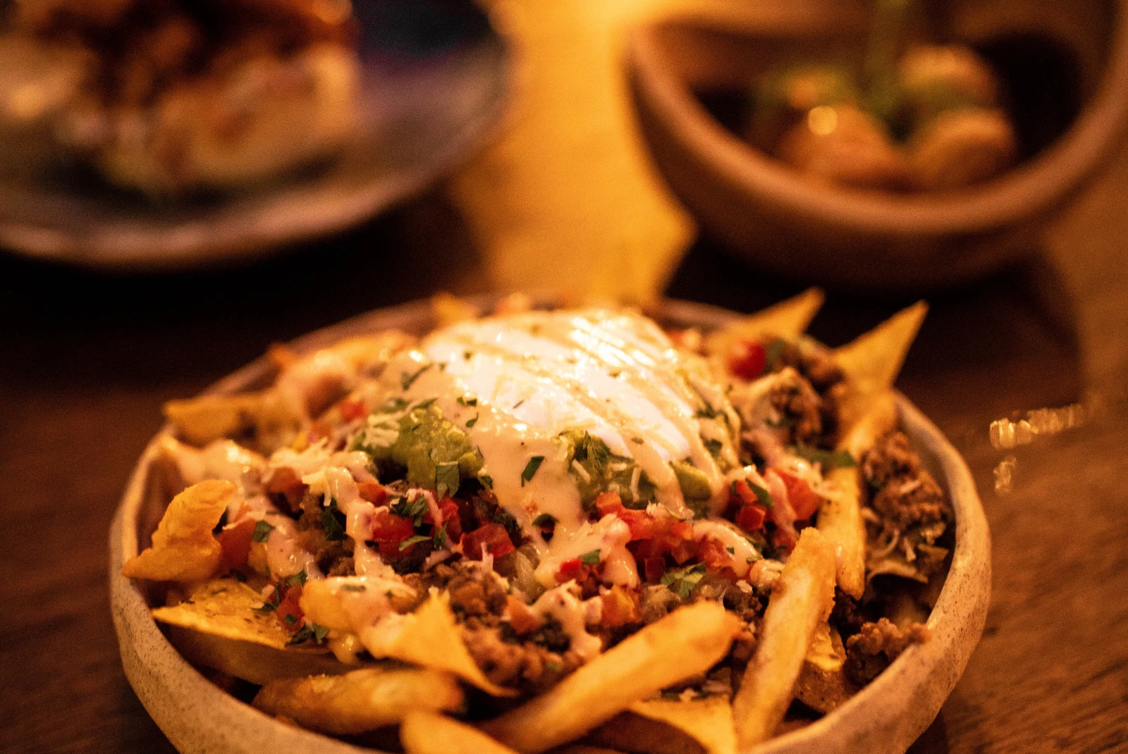 Bowl of fries with toppings on wooden table