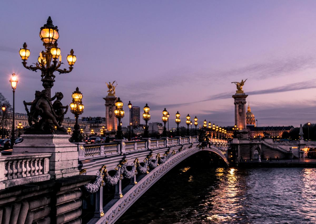 Bridge across canal in Paris with illuminated by streetlights and the city.