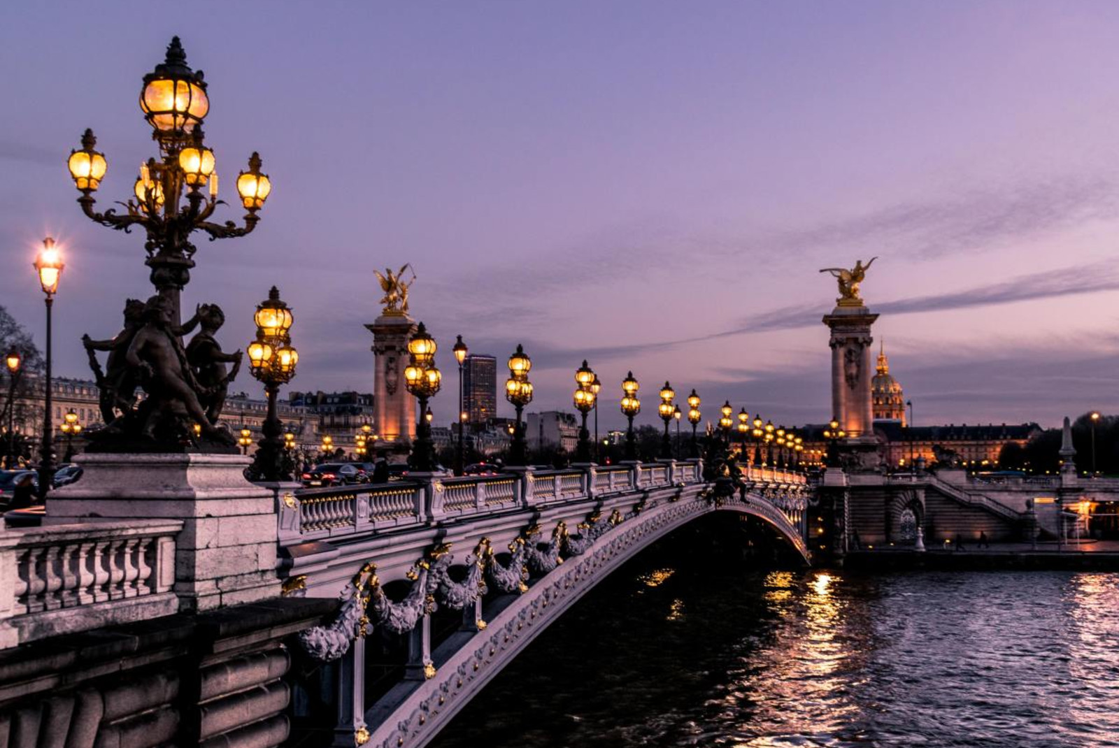 Bridge across canal in Paris with illuminated by streetlights and the city.