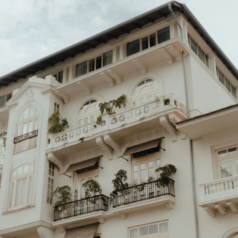 white historic building with small balconies against gray cloudy sky