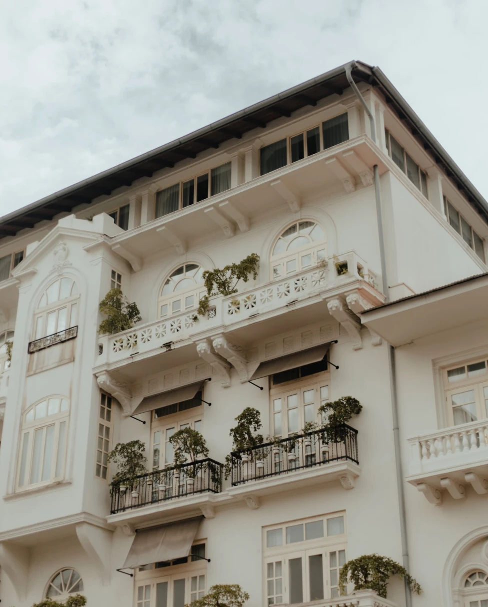 white historic building with small balconies against gray cloudy sky