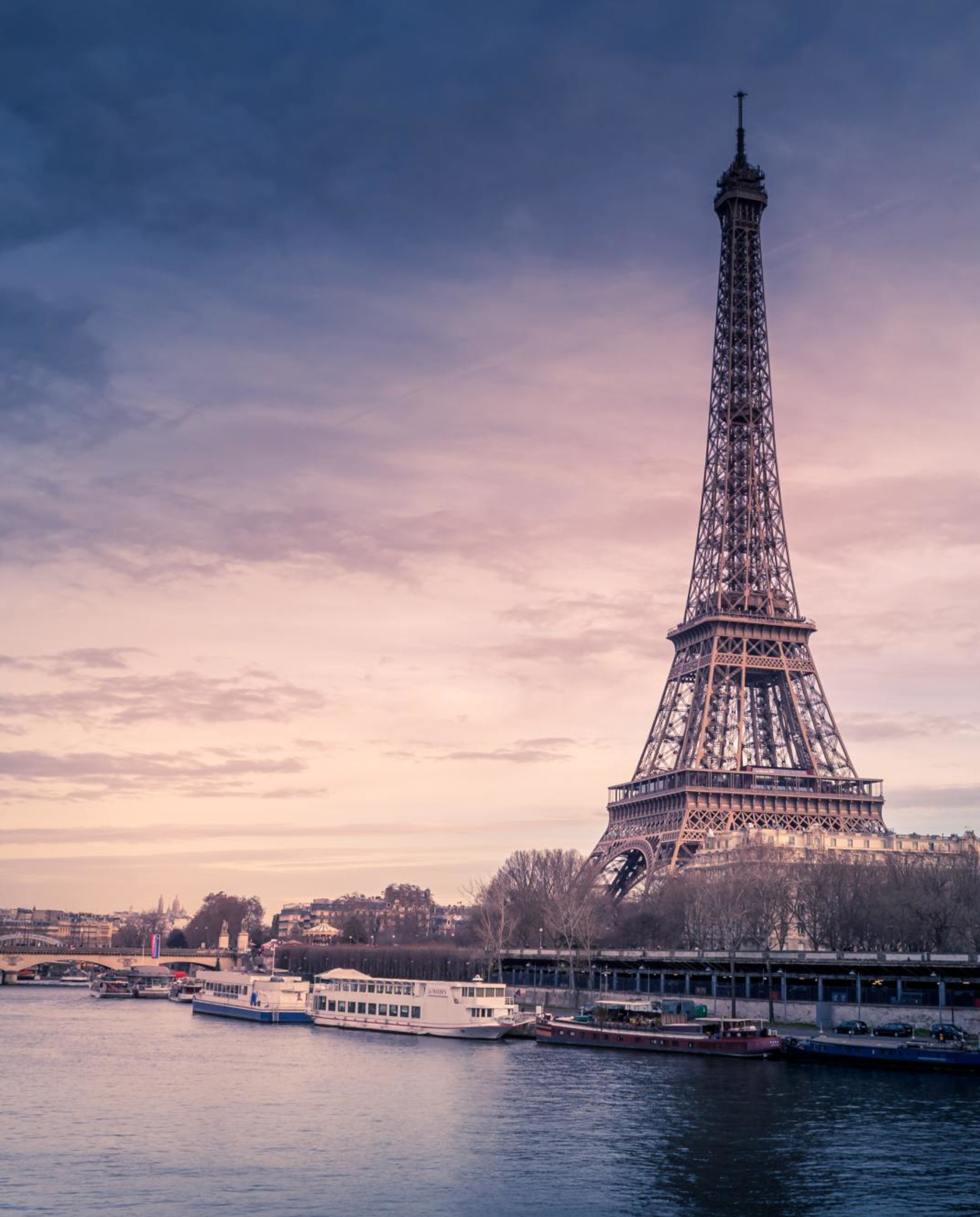 The Eiffel Tower on a dark cloudy day next to La Seine in Paris.