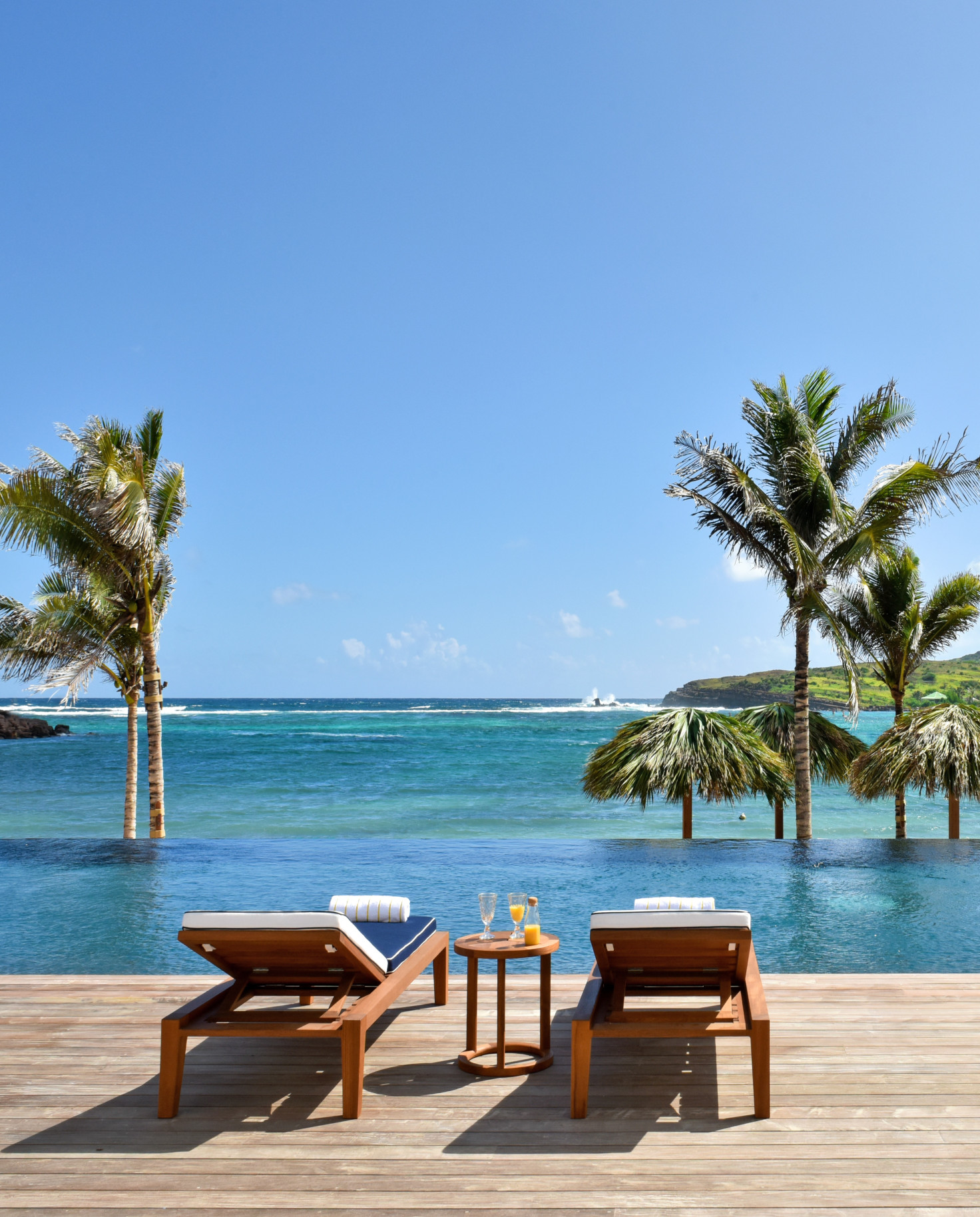 lounge chairs and palm trees next to the ocean during daytime