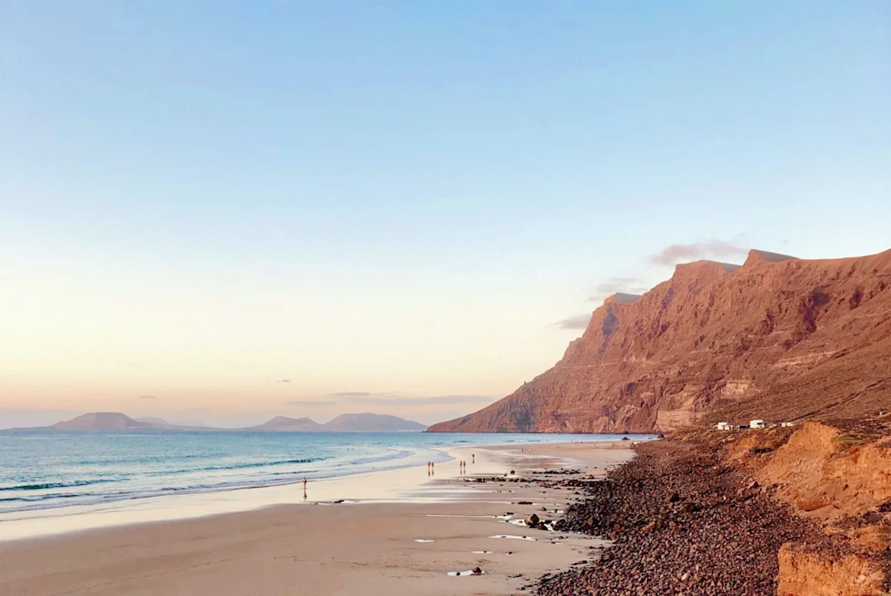 calm wide beach with rocky mountains during golden hour