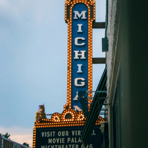 A retro movie theater sign on a building with the word "Michigan" written on it.