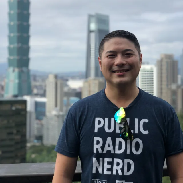 Rick Chen in a blue shirt posing in front of buildings. 