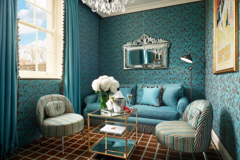 a blue couch in a blue living room with lively wallpaper