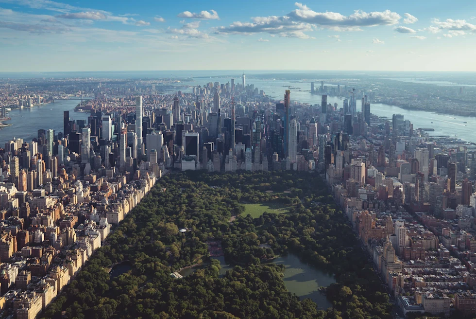 aerial view of skyscrapers and park next to body of water during daytime