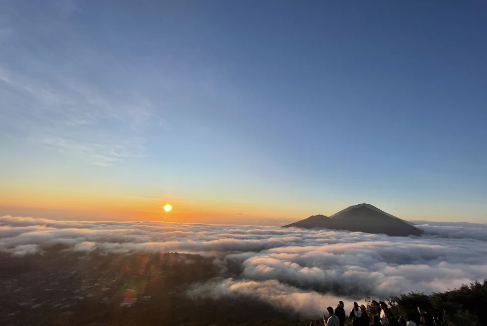 Clouds rising next to a mountain during sunrise