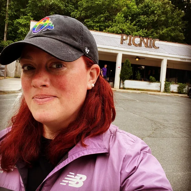 Travel advisor Kate Holland standing in front of a picnic area wearing a colorful hat.