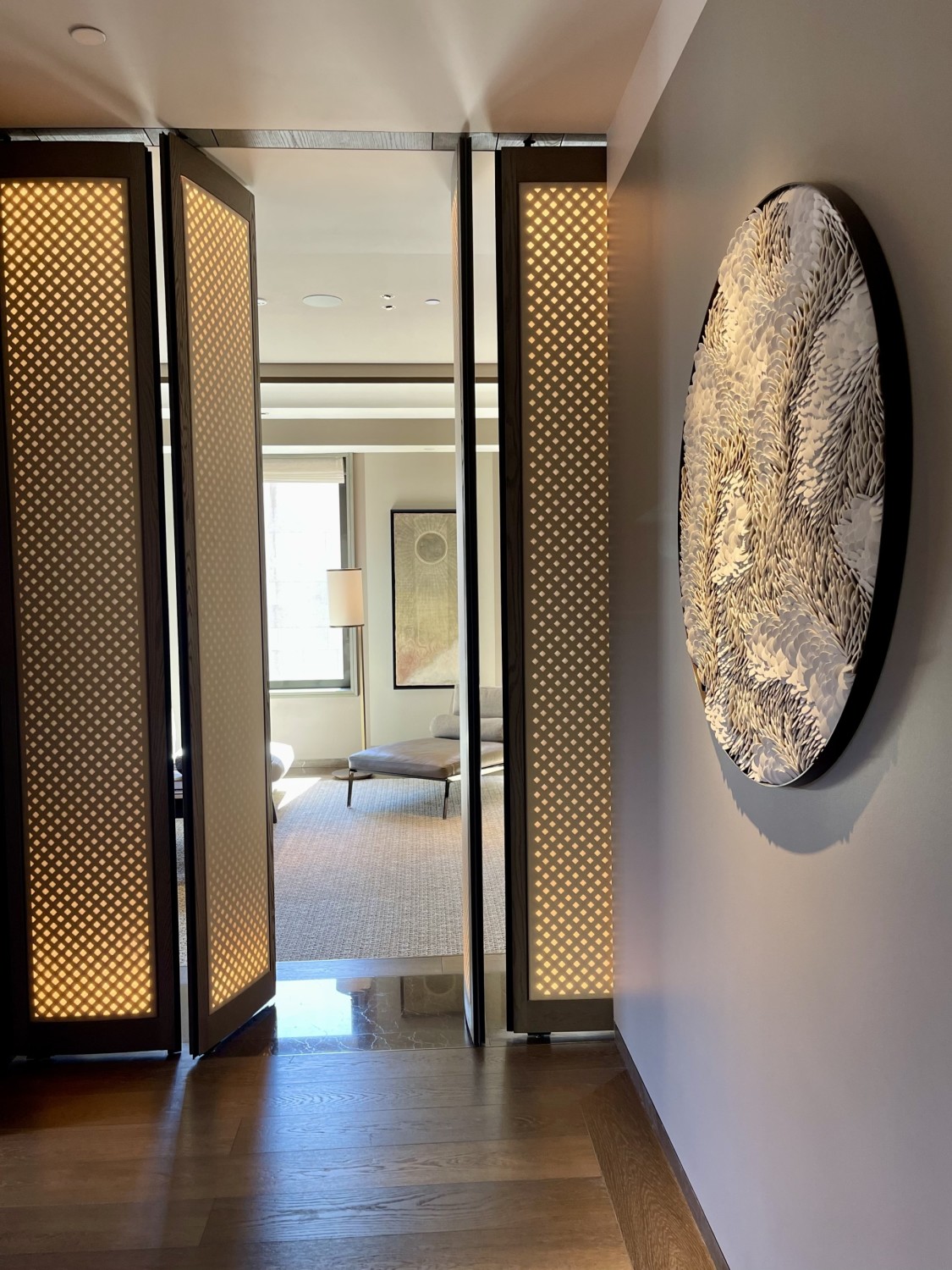 A hallway with an open door that gives a peak inside one of the hotel rooms.